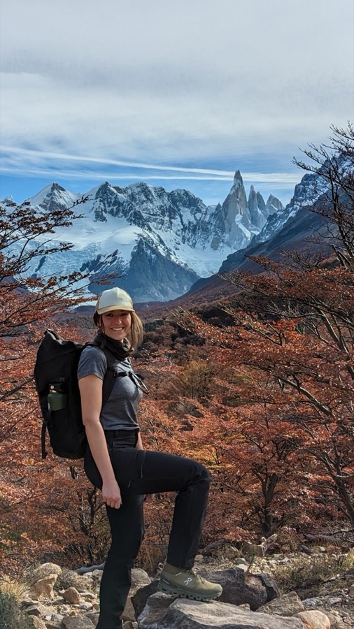 Alexandra hiking through autumn trees with Cerro Torre behind her