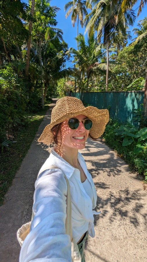 Alexandra in a straw hat on a palm-lined lane